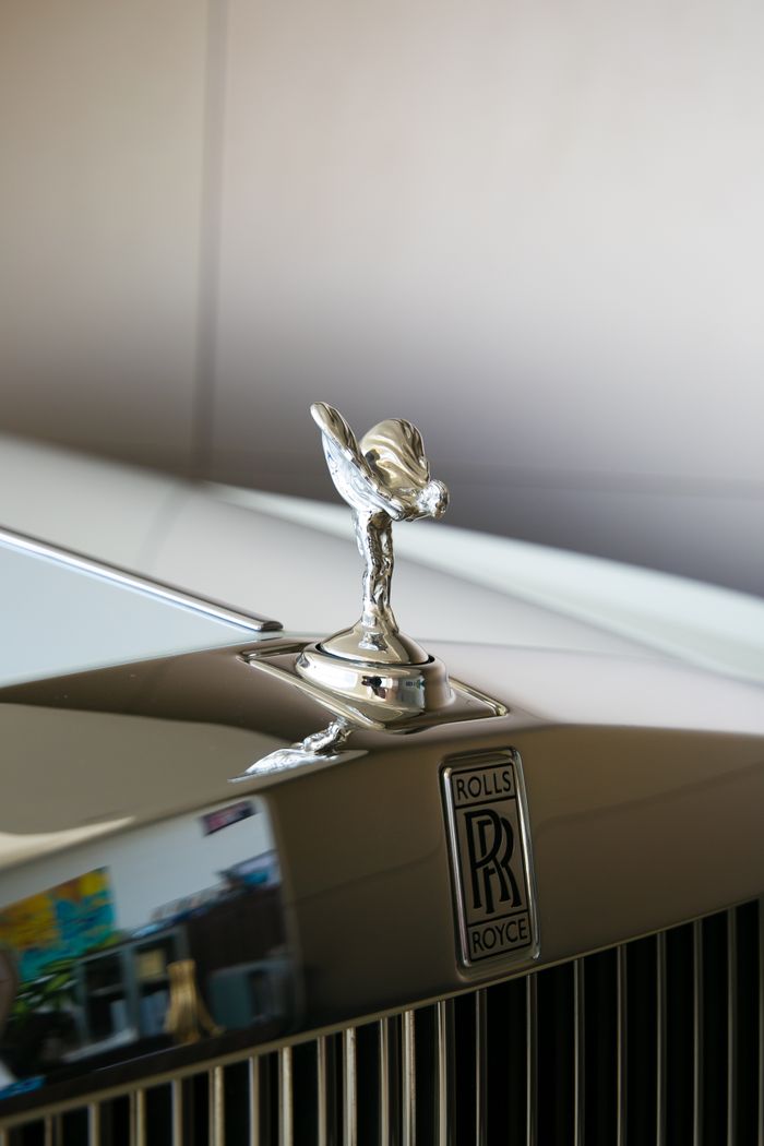 Close-up of Rolls Royce Spirit of Ecstasy ornament on luxury car hood.